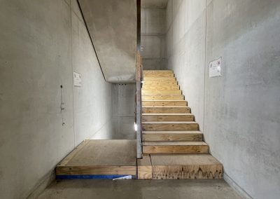 Blick in ein Treppenhaus. Die Wände bestehen aus Sichtbeton und werden nicht verputzt.